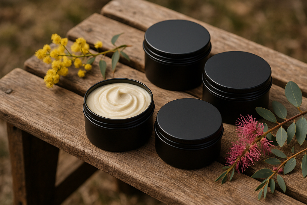 whipped beef tallow in black 100ml tins no label on a rustic wooden bench with australian native flower